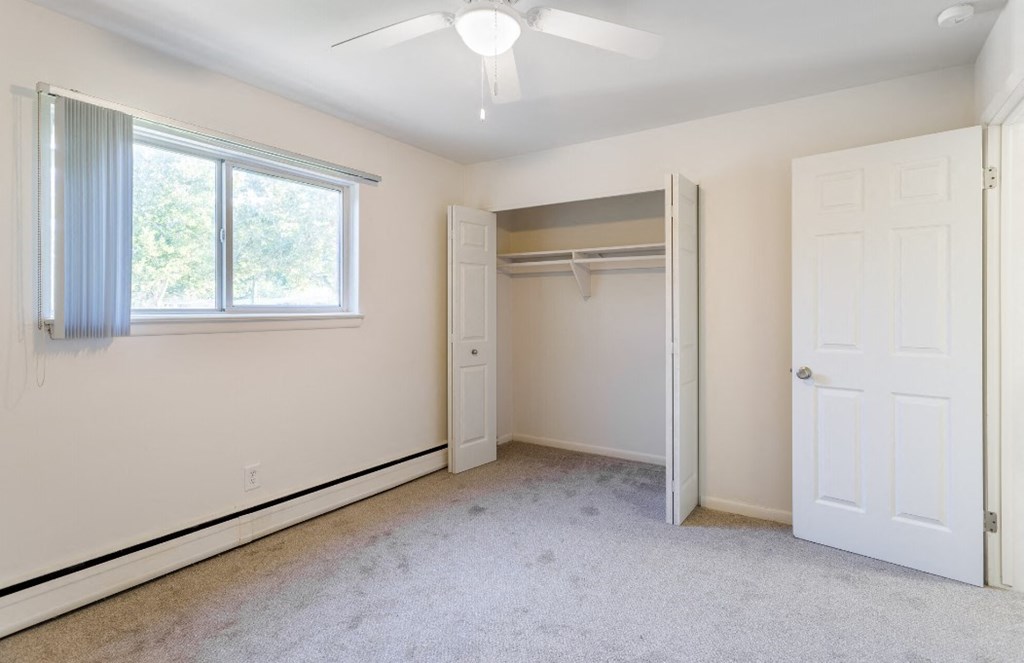 an empty bedroom with a closet and a window and a white door